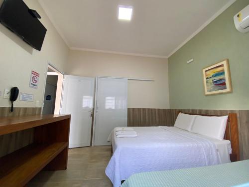 a hotel room with two beds and a television at Residencial Águas de Bare in São Sebastião
