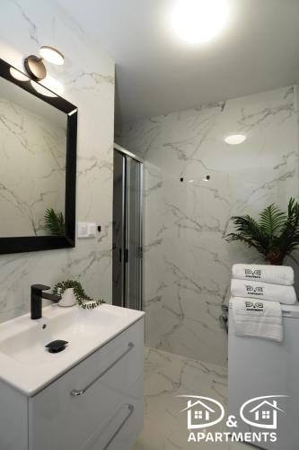 a white bathroom with a sink and a mirror at Pine Tree House 6 in Międzywodzie