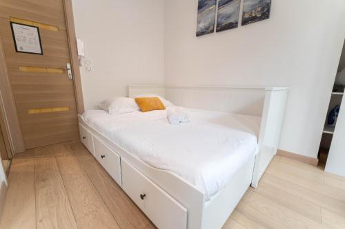 - un lit blanc dans une chambre avec porte dans l'établissement Joli studio au cœur de la vieille ville, à Nice