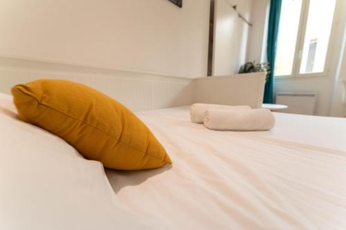 - un lit avec un oreiller jaune et des serviettes dans l'établissement Joli studio au cœur de la vieille ville, à Nice