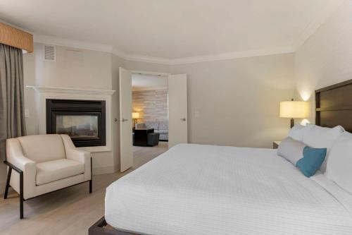 a bedroom with a bed and a chair and a fireplace at Best Western Plus All Suites Inn in Santa Cruz