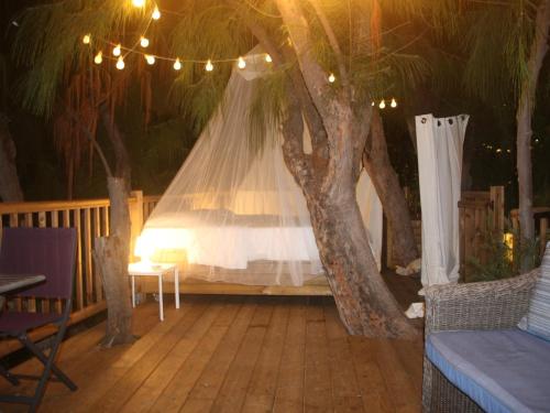 a bed on a deck with a tree at La Villa de la Plage in La Saline les Bains