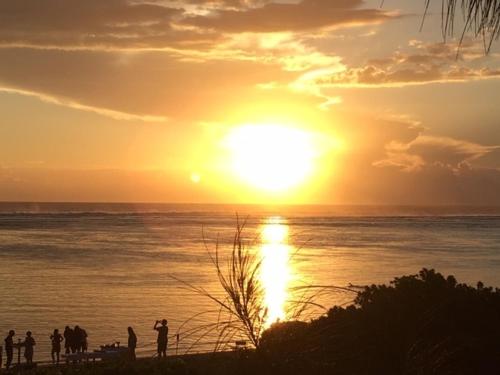 a group of people standing on the beach watching the sunset at La Villa de la Plage in La Saline les Bains
