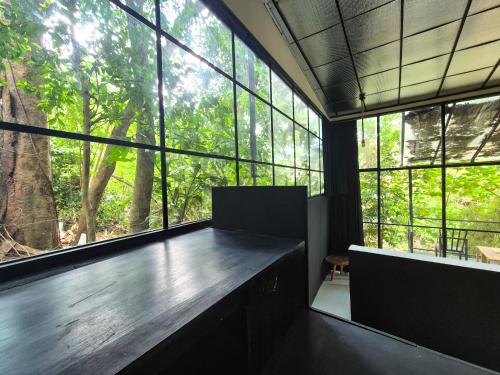 a room with large windows and a wooden table at The Paica in Denpasar