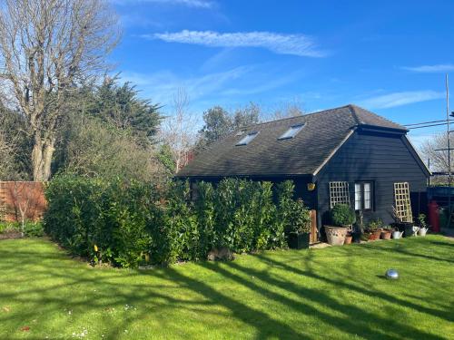 une maison avec une cour avec de l'herbe verte et une maison dans l'établissement Windmill Cottage, à Worthing