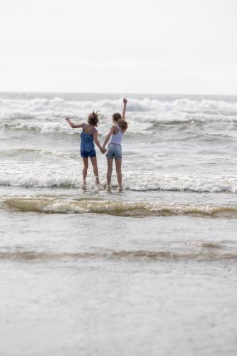 two girls standing in the water at the beach at Sasquatch Shore House in Ocean Shores