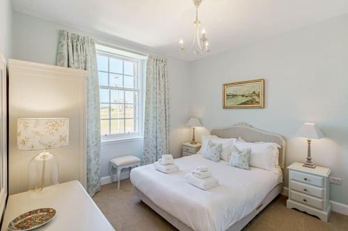 a bedroom with a white bed and a window at Coulter Cottage in Earlsferry