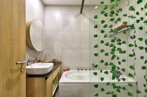 a bathroom with a sink and a shower curtain with leaves at Tranquil Alibaug in Alibag