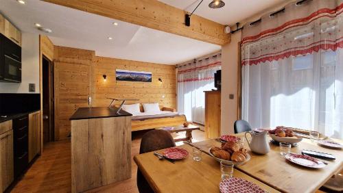 une cuisine et une salle à manger avec une table et un lit dans l'établissement Madame Vacances Grand Studio Maroly, à Courchevel
