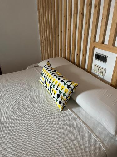 a bed with a yellow and black pillow on it at Hotel Arcos-Coruña in Arcos de la Frontera