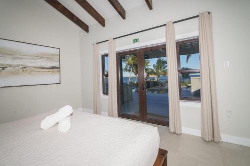 a bedroom with a white bed and a large window at Casa de Wilson - 5 Bedroom Beachfront Villa in Maya Beach