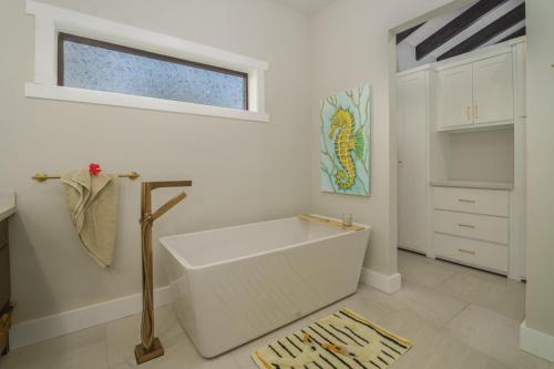 a white bathroom with a tub and a window at Casa de Wilson - 5 Bedroom Beachfront Villa in Maya Beach