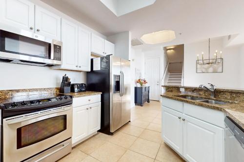 a kitchen with white cabinets and a stainless steel refrigerator at St Lucia at Silver Shells in Destin
