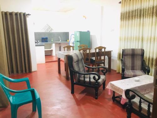 a living room with chairs and a table and a kitchen at Sakula Villa Inn in Weligama