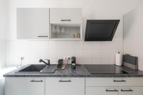 a white kitchen with a sink and a tv at JAMA - Designapartment im Herzen der Stadt in Schweinfurt