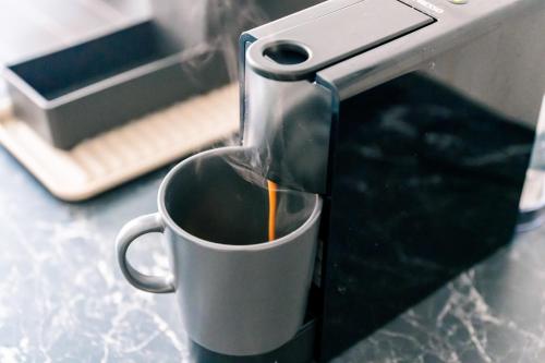 a cup of coffee is being brewed in a coffee machine at JAMA - Designapartment im Herzen der Stadt in Schweinfurt