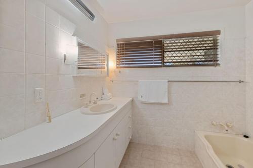 a white bathroom with a sink and a bath tub at Charming 4BR House with Parking near Sunnybank in Brisbane