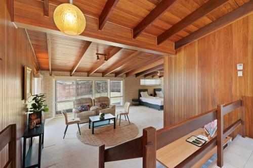 a living room with wood paneling and a table and chairs at Charming 4BR House with Parking near Sunnybank in Brisbane