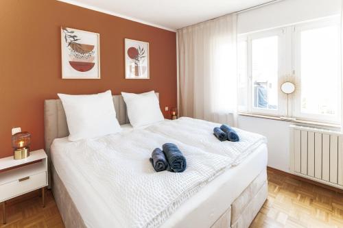 a bedroom with a large white bed with two blue slippers at JAMA - Designapartment im Herzen der Stadt in Schweinfurt