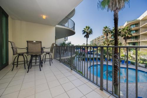 un balcone con tavolo e sedie accanto alla piscina di Phoenix on the Bay 1223 condo a Orange Beach