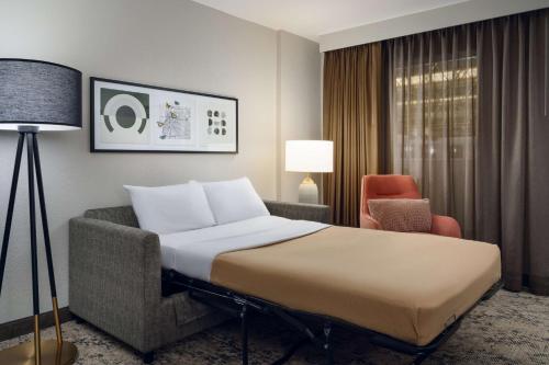孟菲斯Embassy Suites by Hilton Memphis East Germantown Area的一间带床和椅子的酒店房间