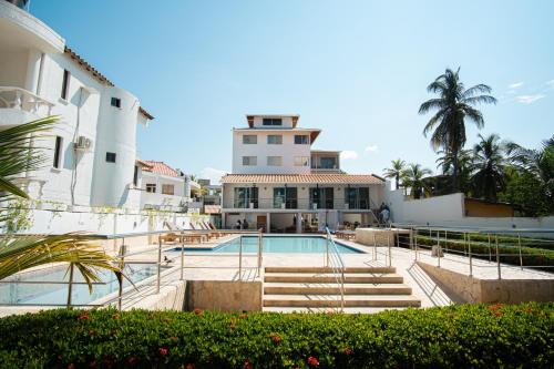 a house with a swimming pool in front of a building at Hotel Caribe Coveñas in Coveñas