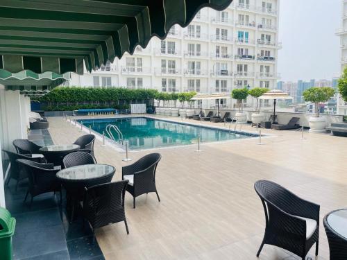 a hotel patio with tables and chairs and a swimming pool at Golden Penthouse - Couple Friendly - DLF My Pad, Gomtinagar, Lucknow in Lucknow