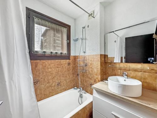 La salle de bains est pourvue d'un lavabo blanc, d'une baignoire et d'un miroir. dans l'établissement RB111 - Studio 4 Pers centre Carroz, aux Carroz d'Arâches