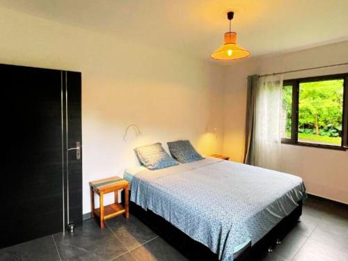 a bedroom with a large bed and a window at Villa Les Jardins de la Trinité in Saint-Philippe
