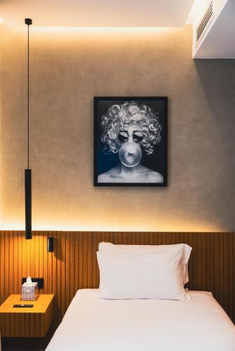 a bedroom with a bed with a picture on the wall at J Maluni City Hotel in Rome