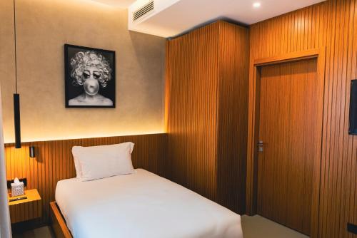 a small bedroom with a white bed and wooden walls at J Maluni City Hotel in Rome