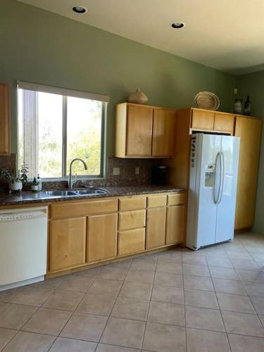 a kitchen with wooden cabinets and a white refrigerator at Tucson Mnt Foothills Saguaro Bliss in Tucson