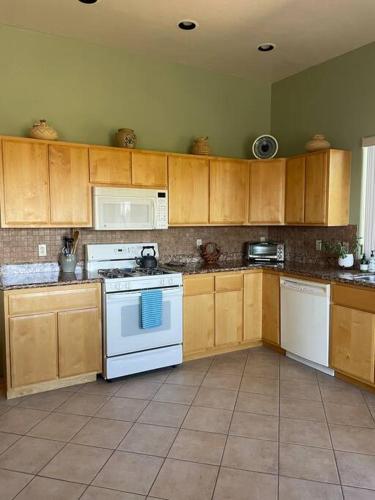 a kitchen with white appliances and wooden cabinets at Tucson Mnt Foothills Saguaro Bliss in Tucson
