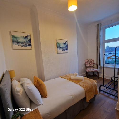 a bedroom with a bed and a chair and a window at 5 Bed Plymouth Home-Free Parking - Close to City Centre in Plymouth