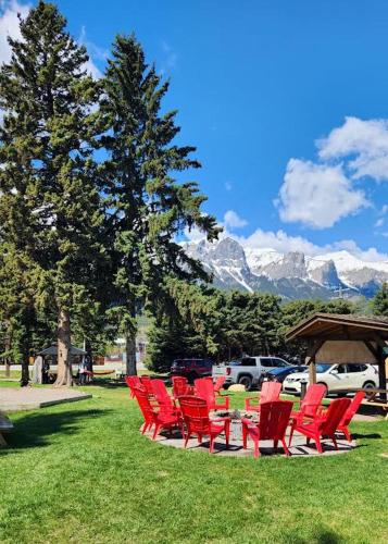 a group of red chairs and a gazebo with mountains at Rundle Mountain Lodge in Canmore