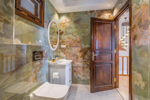 Un baño con inodoro, lavabo y espejo. en White Garden Villas, en Kas