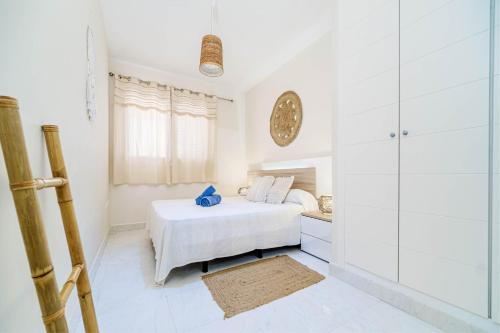 a white bedroom with a bed and a glass wall at Ático Balinés con vistas al mar in Canet de Berenguer