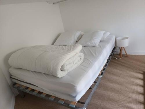 - un lit avec des draps et des oreillers blancs dans l'établissement Studio Hyper centre, quartier historique, à La Rochelle