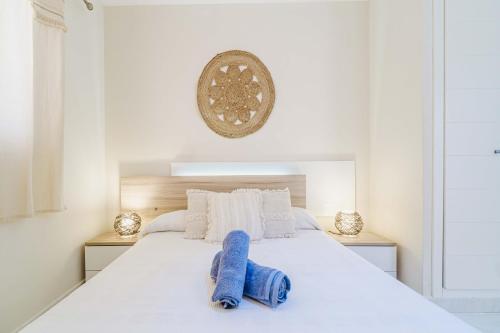 a white bed with two blue towels on it at Ático Balinés con vistas al mar in Canet de Berenguer