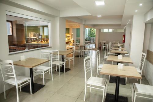 a restaurant with wooden tables and white chairs at Parque Hotel Cordeiro in Cordeiro