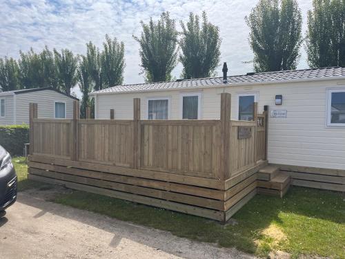 a wooden deck with a fence next to a house at vakantiehuisje tis ier goed in Jabbeke