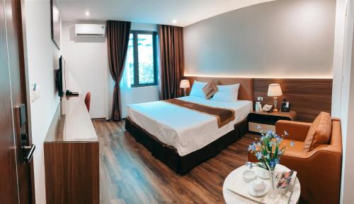 a hotel room with a bed and a chair at LuxTel Hotel Tây Hồ in Hanoi