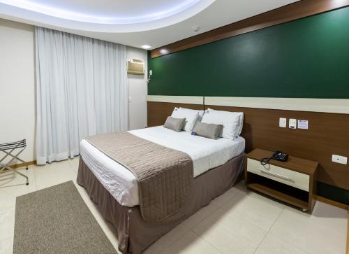 a bedroom with a large bed and a green wall at Centromar Hotel in Balneário Camboriú