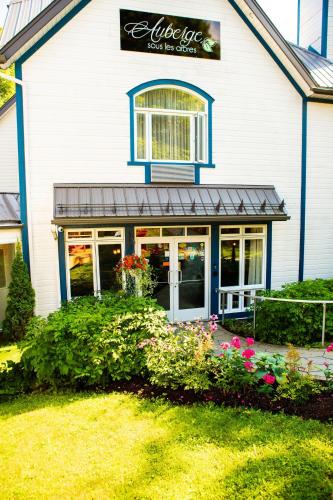 a white house with flowers in front of it at Auberge Sous les Arbres in Gaspé