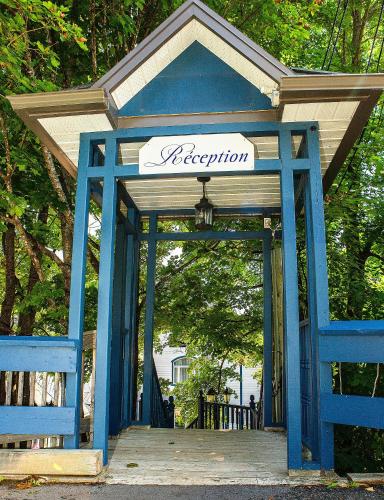 a blue gate with a sign that reads reception at Auberge Sous les Arbres in Gaspé