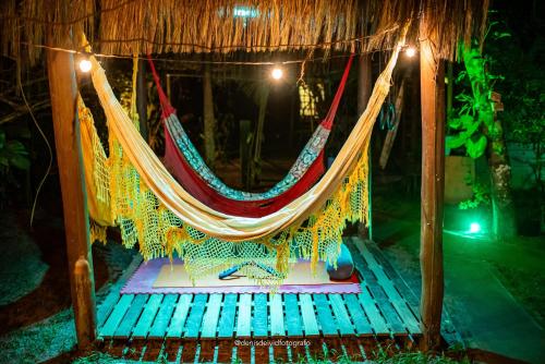 a hammock hanging from a thatch roof at Pousada D'Aconchego Nova Brasilia in Ilha do Mel