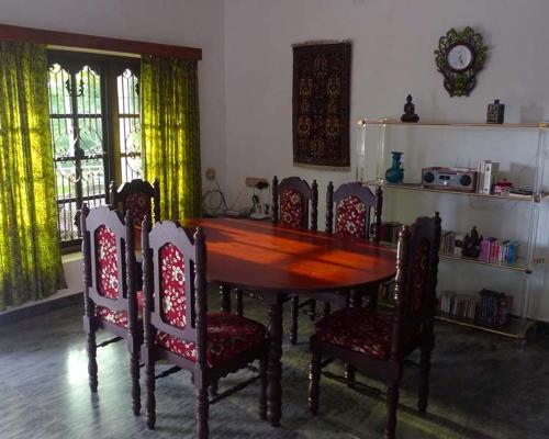 a dining room with a wooden table and chairs at whispering kera in Pūvār