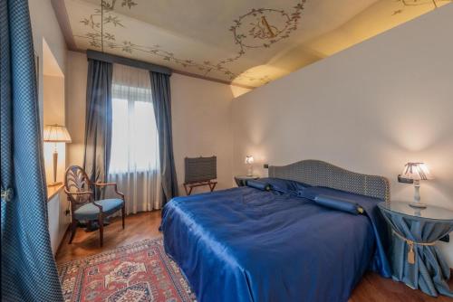 a hotel room with a blue bed and a chair at Palazzo Finati in Alba