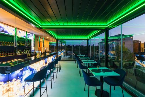 a restaurant with green lighting and tables and chairs at J Maluni City Hotel in Rome
