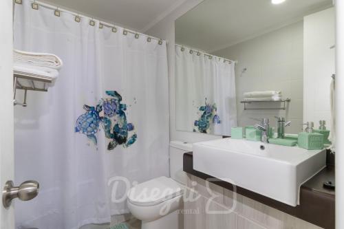 ein Badezimmer mit Waschbecken, Toilette und Duschvorhang in der Unterkunft Disegni 06 - Departamento vista al mar y Casino Enjoy La Serena in Coquimbo